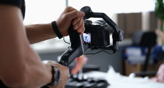 Photographer shooting video on camera from tripod closeup. Professional photographic equipment concept